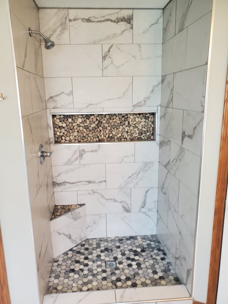 Custom marble tile shower with river rock accent niche